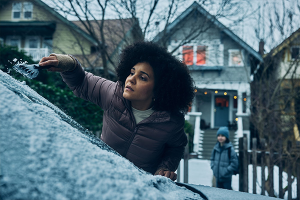 woman clearing off ice from car